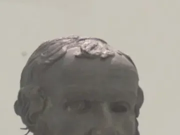 Bronze head of the Porticello Philosopher with curly beard and hollow eyes