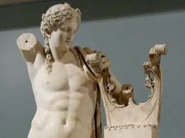 Apollo of Cyrene marble statue holding a lyre stand with a coiled serpent, shown with one arm missing.