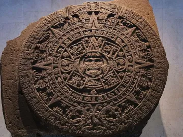 The Aztec Sun Stone carved as a large circular stone disc with a central face and concentric rings of symbols.