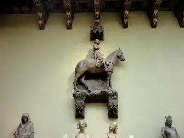 Stone equestrian statue of the Bamberg Horseman mounted on a wall, with a crowned figure on horseback and carved architectural details above.