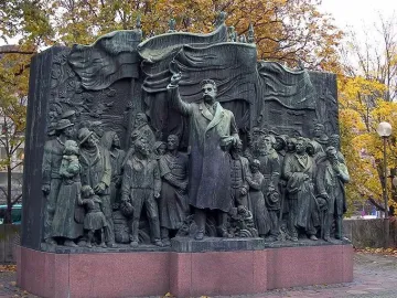 The Branting Monument in bronze, showing a central figure with a raised arm addressing a crowd of men, women, and children.