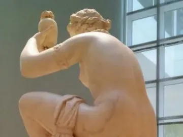 Giambologna\'s Venus seated on a column, wrapped in drapery and turned to the left.