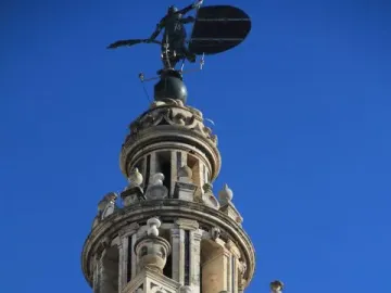 The Giraldillo weather vane atop the Giralda tower in Seville against a clear blue sky.