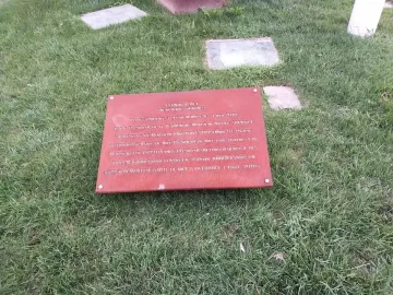 A reddish-brown information plaque for Neuf Lignes Obliques lies angled on green grass.