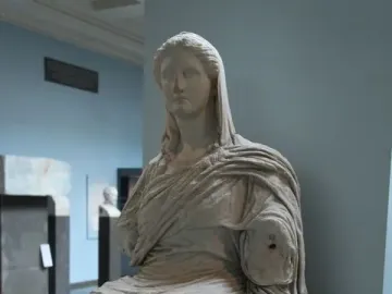 Demeter of Knidos seated marble statue with draped garments and missing forearms in a museum display