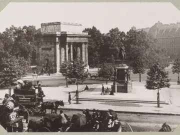 The Duke of Wellington equestrian statue in front of Wellington Arch, with carriages and pedestrians on a London street.