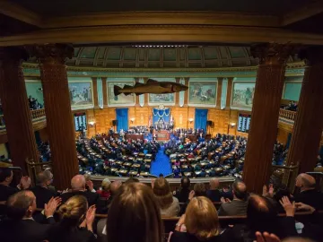 Sacred Cod fish sculpture hanging in a legislative chamber with rows of seated people