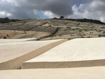 Il Grande Cretto stretching across a hillside in cracked concrete forms under a partly cloudy sky.