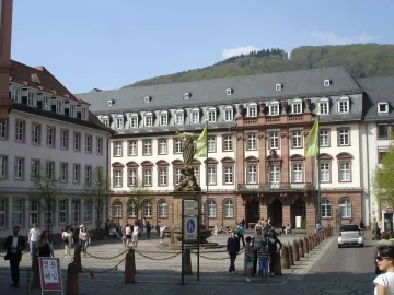 Kornmarkt Madonna on a tiered pedestal in a cobblestone square, with a crowned robed figure holding a smaller figure.