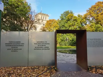 Entrance to the Memorial to the Murdered Sinti and Roma of Europe, with a dark archway and panels of text beside a circular water basin.
