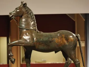 Bronze horse statue from the Neuvy-en-Sullias Hoard, shown with one front leg raised on a rectangular base.