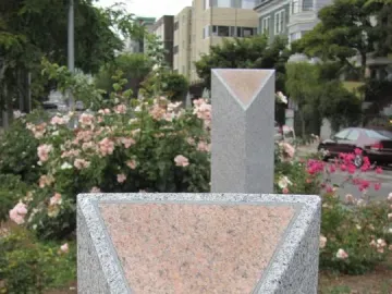 Pink Triangle Park memorial with two gray granite columns topped by pink triangles, set among grass and roses.