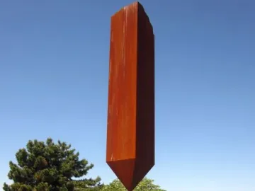 Broken Obelisk sculpture with a rust-colored metal base and tall rectangular column against a blue sky