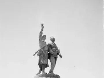 Demba et Dupont monument showing two military figures atop a tall stone pedestal with plaques and inscriptions.