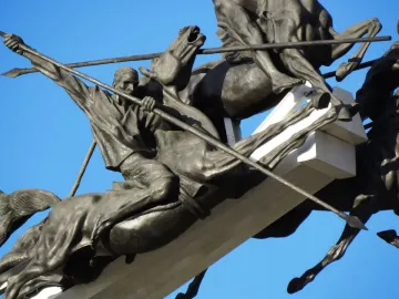 Bronze horsemen statues from the Vargas Swamp Lancers monument against a blue sky.