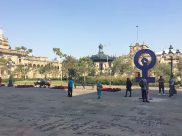 Antimonumenta, a large purple feminist symbol with a raised fist, stands in a public plaza covered in graffiti-like markings.