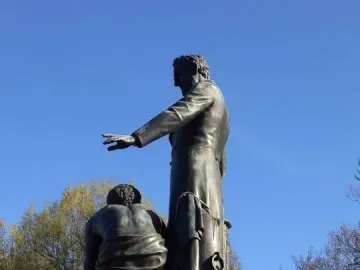 Emancipation Memorial bronze statue with Abraham Lincoln standing beside a kneeling figure on a stone pedestal.