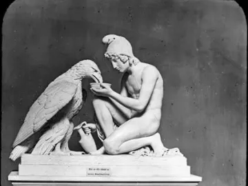 Ganymede with Jupiter’s eagle, a white sculpture of a kneeling nude youth offering a bowl to a large eagle on a pedestal.