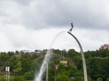 God our Father on the Rainbow sculpture with a water jet arcing from the raised figure into the bay.