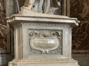 Marble pedestal with the inscription Sanctvs Longinvs Martyr, set above ornate black metal grates.