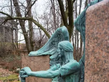 Haserot Angel, a weathered green-patinated winged figure beside a polished stone monument.