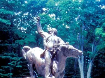 Israel Putnam equestrian statue of a man on horseback with one arm raised, set on a stone base amid trees and greenery.