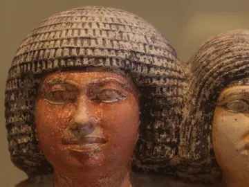 Close-up of the heads of the Raherka and Meresankh statues with textured headdresses and painted facial details.