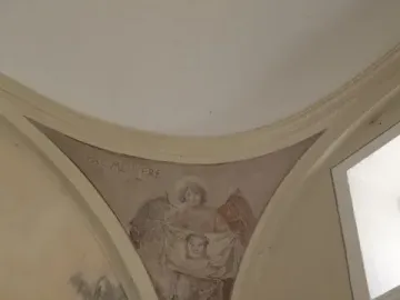 Faded fresco of an angel holding a cloth with a face, with the Latin inscription \