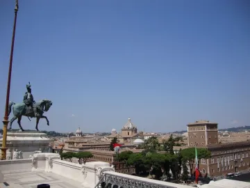 Victor Emmanuel II equestrian statue on a white marble pedestal overlooking Rome under a clear blue sky.