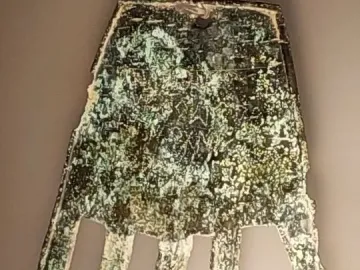 The Hand of Irulegi, an ancient hand-shaped artifact with engraved markings and a corroded green-brown surface.
