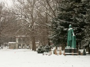 Lincoln the Lawyer statue standing in a snow-covered park beside a rectangular pillar.