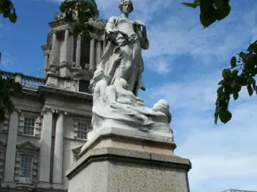 Titanic Memorial in Belfast, showing a robed female figure holding a laurel wreath above smaller figures on a granite pedestal.