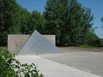Hailfingen-Tailfingen Memorial with a textured triangular metal sculpture in front of a concrete wall.