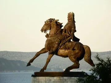 Tatishchev Monument showing a man in period clothing riding a rearing horse beside a wide river.