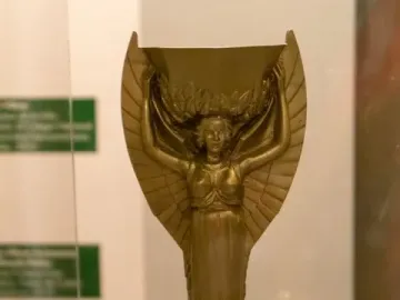 Jules Rimet Trophy with a winged female figure holding a laurel wreath above a spherical FIFA base.