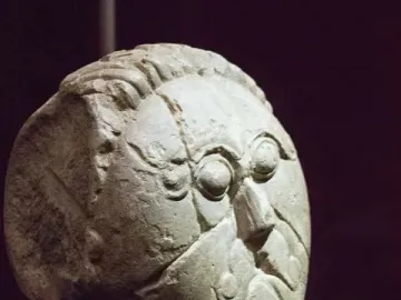 Mšecké Žehrovice Head with carved eyes, nose, and hairstyle on a dark stand.