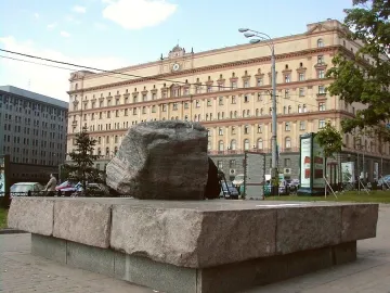 Solovetsky Stone monument, a large granite boulder on a stone base, with a beige building in the background.
