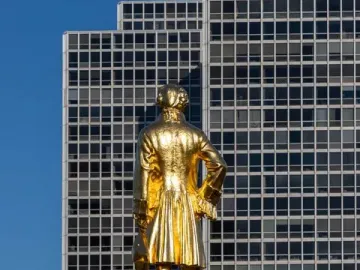 Alexander Hamilton Memorial statue of a man in period clothing holding a tricorn hat on a dark pedestal.
