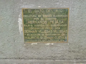 Weathered bronze plaque mounted on a textured light gray wall, with engraved Spanish text and names.