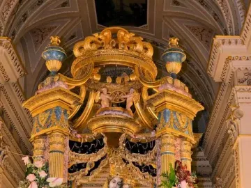 Madonna dell\'Udienza sculpture of the Madonna and Child displayed in a gilded shrine with flowers and crowns.