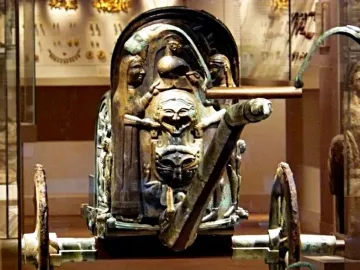 Front portion of the Monteleone Chariot with an ornate sculpted panel, mask-like faces, and a visible shaft extending forward.