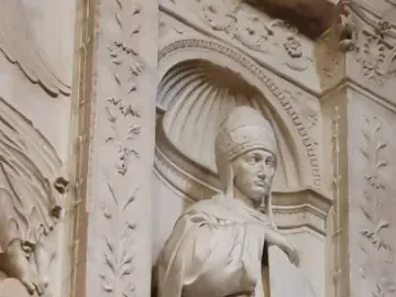 Saint Gregory stone sculpture of a robed figure holding a closed book in a carved niche with floral columns.