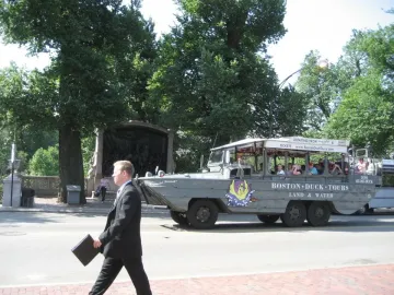 The Shaw Memorial appears behind trees and a stone wall, with a Boston Duck Tours vehicle passing in front.
