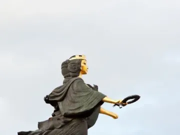 Statue of Sofia, a monumental female figure with a gilded face and crown, holding a wreath on a tall pedestal.