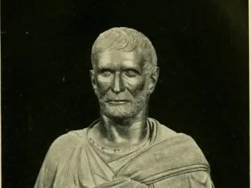 Capitoline Brutus bust with short wavy hair, a bearded stern face, and a draped garment on an ornate stand.