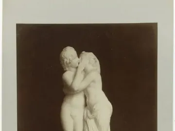 Cupid and Psyche marble sculpture showing two youthful figures embracing and kissing.