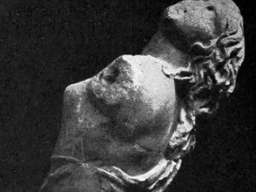 Partial stone sculpture of the Dancing Maenad shown in profile, with arched back and long hair swept backward.