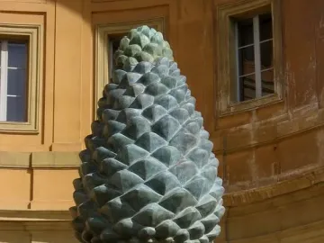 La Pigna bronze pine cone sculpture on an ornate carved stone base, flanked by two peacock statues.