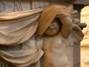 Marble relief on the Tomb of Ferdinand van den Eynde showing a putto peeking from beneath draped cloth beside inscribed text.