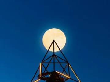 The Tetrahedron in Bottrop illuminated at twilight with a bright full moon above its apex.